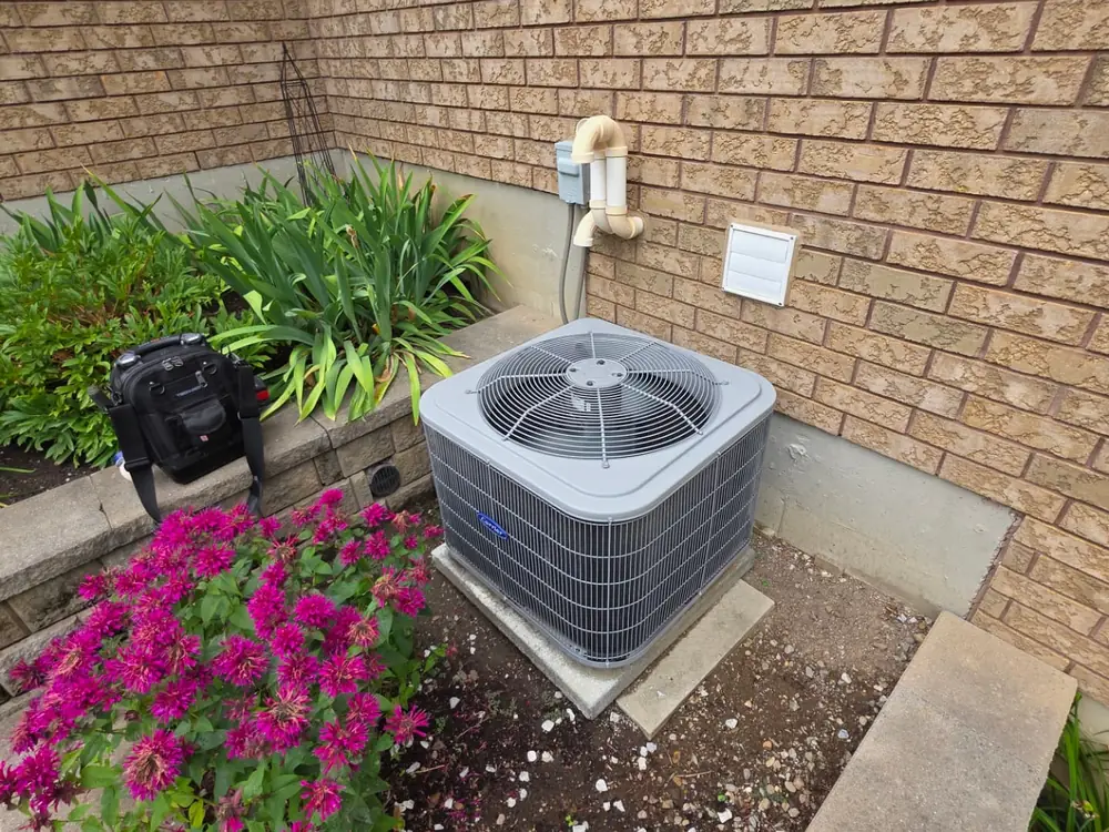 Air conditioner condenser installed beside a brick wall during a summer AC installation in Simcoe County